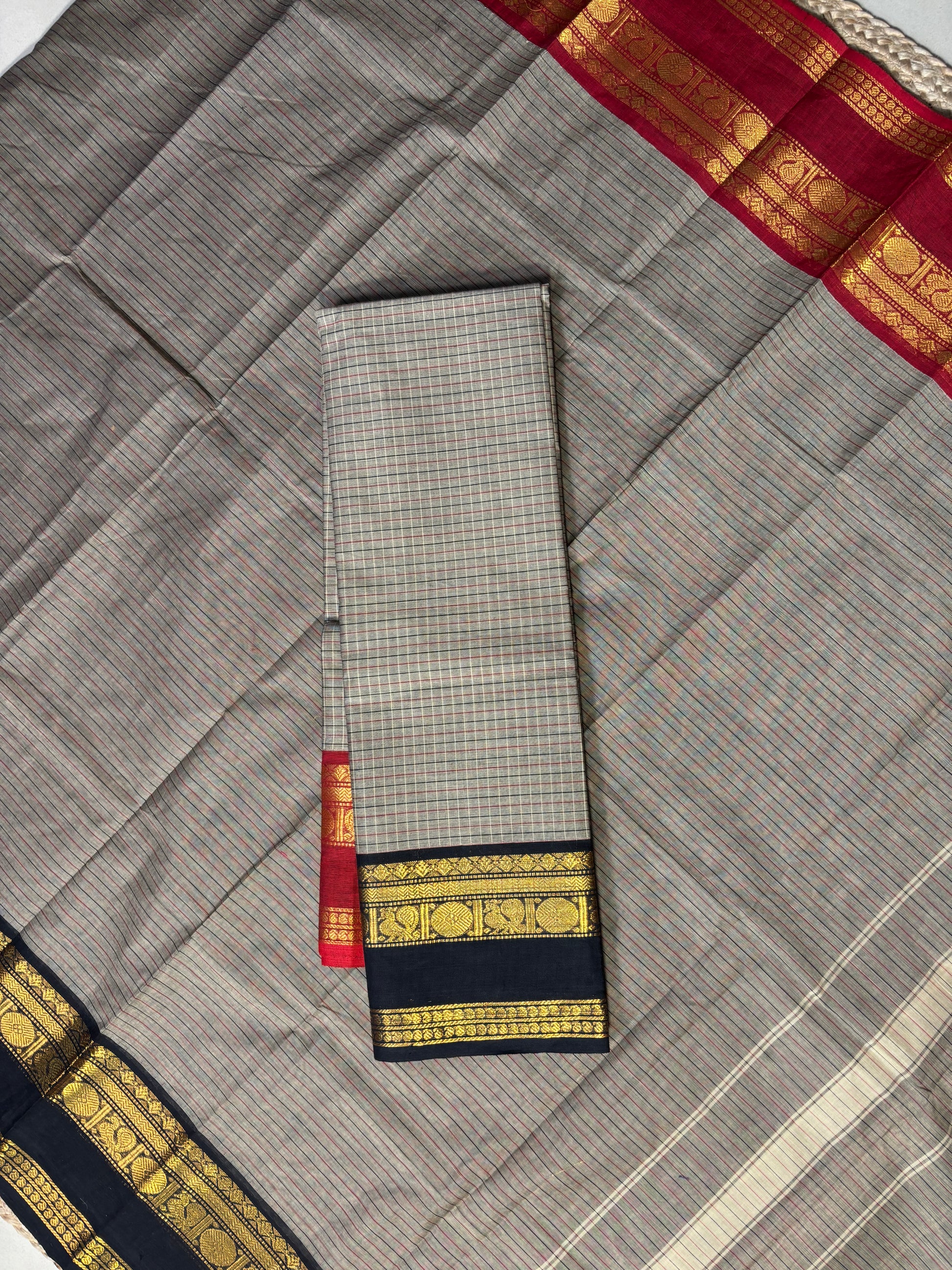 Gray saree with gold and red border on a plain background